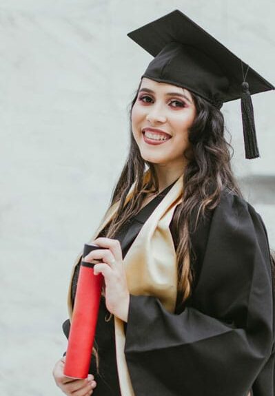 happy graduate who looks ready to learn English language Skills who is holding new diploma in graduation outfit